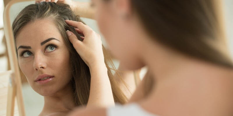 woman checking her hair in the mirror