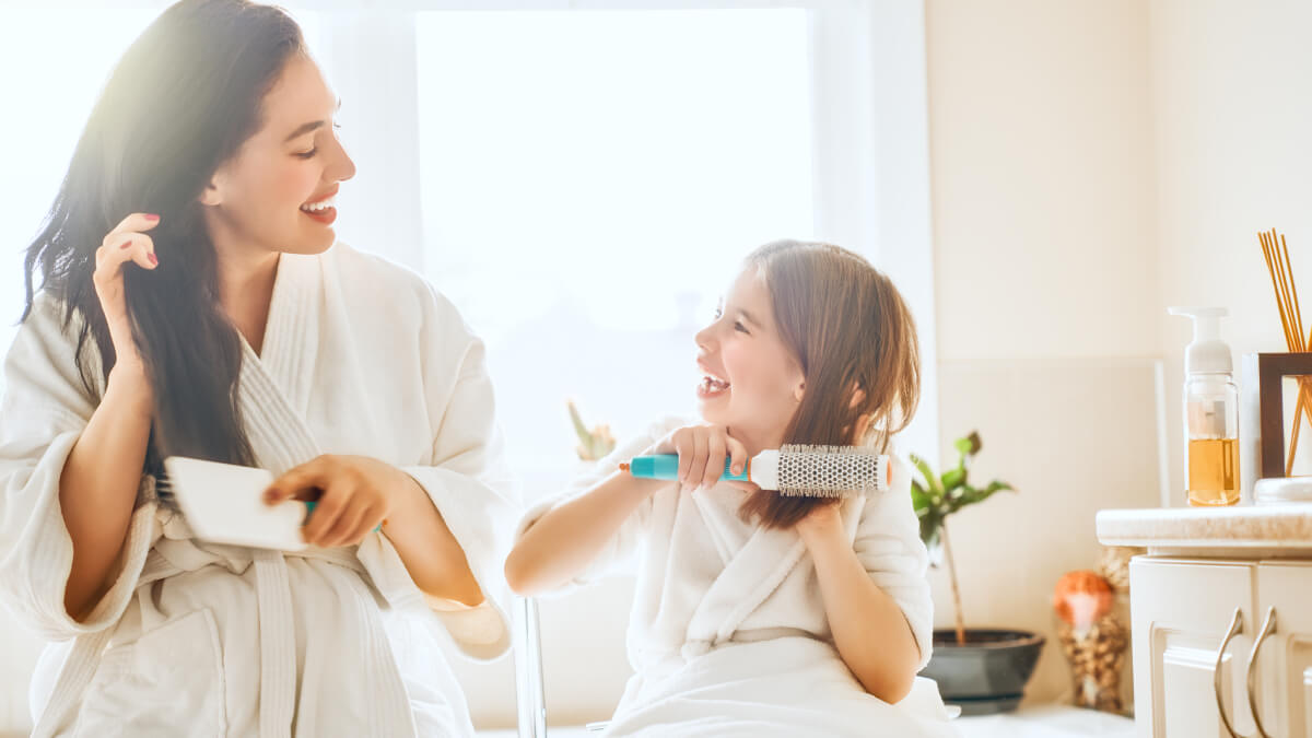 Mother and daughter brushing hair